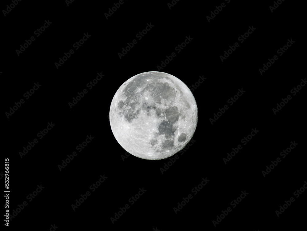 Obraz premium Full moon on the black night sky shining bright. The surface structure is visible of the Earth's natural satellite. Craters caused by impacts are observable. A detailed close-up from Germany.