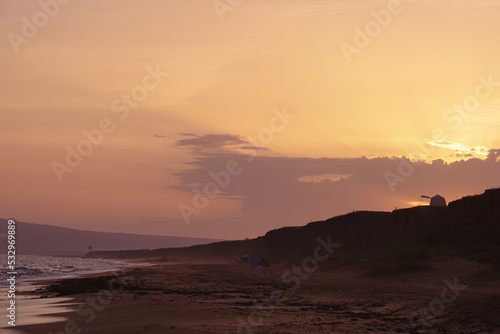 Majestic sunset scene over the mountain on which there is a tourist tent on the seashore