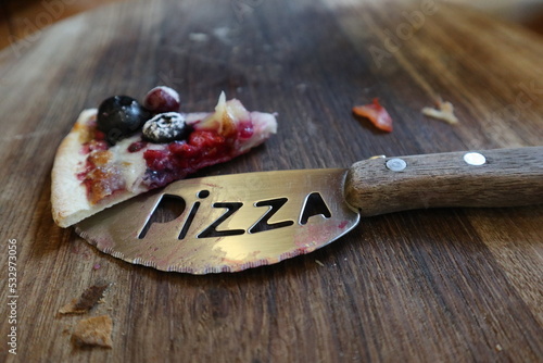 blue barry Pizza on the wooden plate close-up with pizzacutter photo