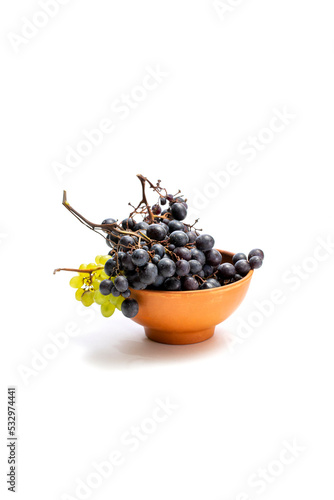 Bunches of ripe grapes in a brown plate on a white background