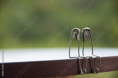 Safety pin couple sitting on table with customizable space for text and ideas. Love and romance concept