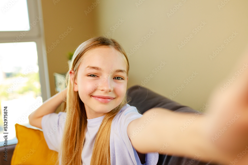 pre-teen girl making selfie photos on her smartphone in cozy living room at home pre-teen girl making selfie photos on her smartphone in cozy living room at home