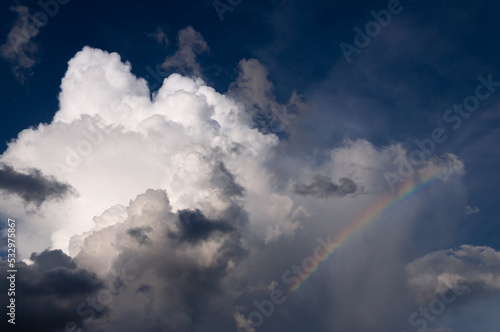 White huge cumulonimbus cloud with the rainbow, rising up in the dark blue sky. Cloudscape, Japan © lemacpro
