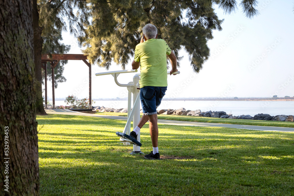 Senior man in sportswear being exercise on apparatus in the park. Quality of life concept.