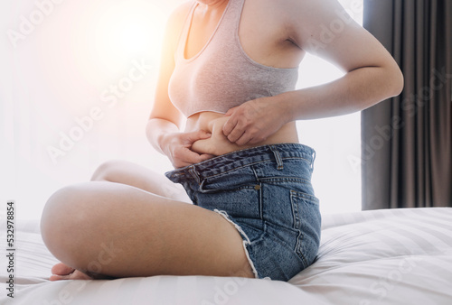 Quadro em tela Beautiful fat woman with tape measure She uses her hand to squeeze the excess fat that is isolated on a white background