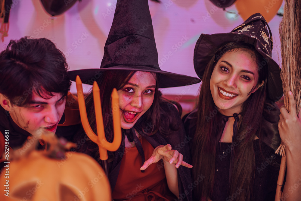 Obraz premium Asian young people in costumes celebrating halloween. Group of friends having fun at party in nightclub.