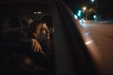 Woman portrait in a car relaxing looking through window at the night 