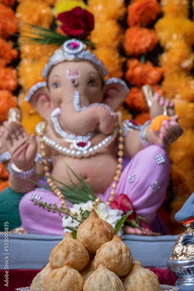 A Beautiful clay statue/Idol of an Indian god Lord Ganesha decorated with colourful Marigold garland A Beautiful clay statue/Idol of an Indian god Lord Ganesha decorated with colourful Marigold garland