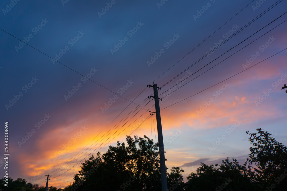 Poles and power lines against the background of the evening sky.