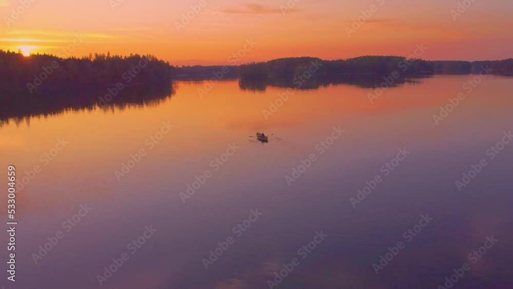 A man rowing on a calm lake at sunset. Aerial footage. A man rowing on a calm lake at sunset. Aerial footage.