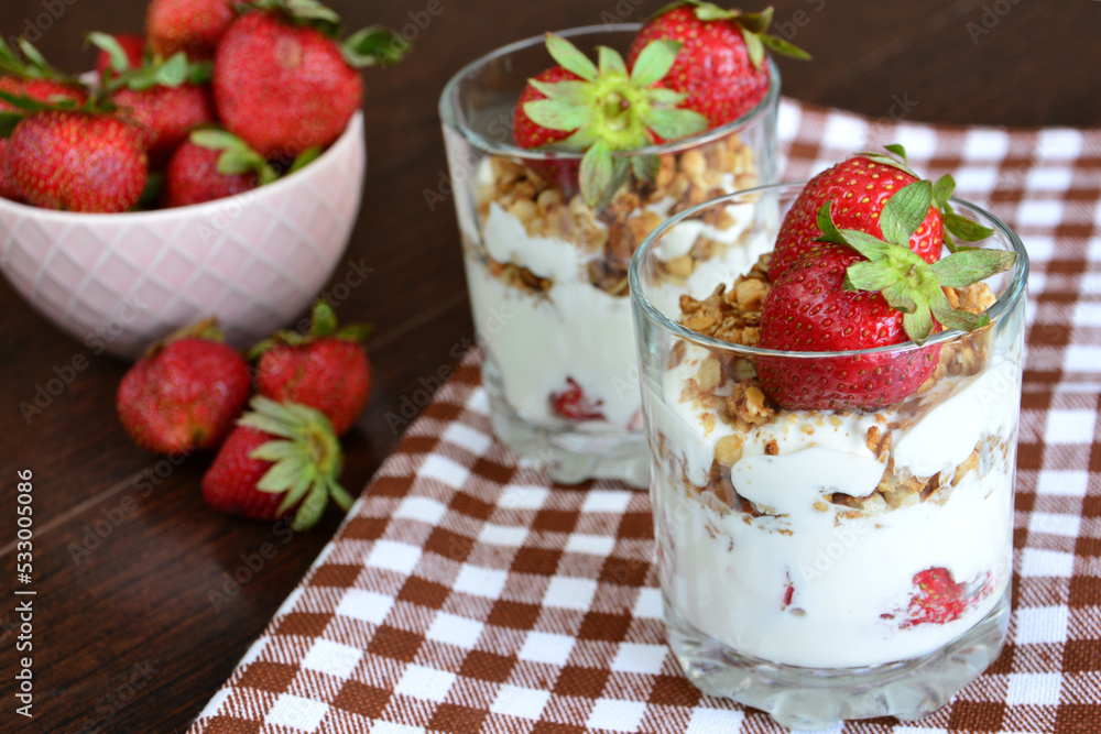 healthy dessert with yoghurt, granola and strawberry in drinking glasses, close-up healthy dessert with yoghurt, granola and strawberry in drinking glasses, close-up