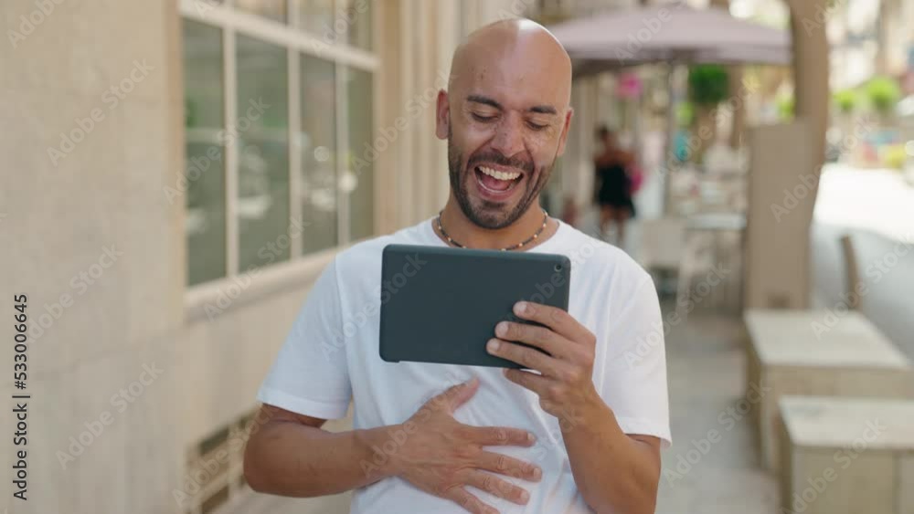 Young bald man smiling confident watching video on touchpad at street Young bald man smiling confident watching video on touchpad at street