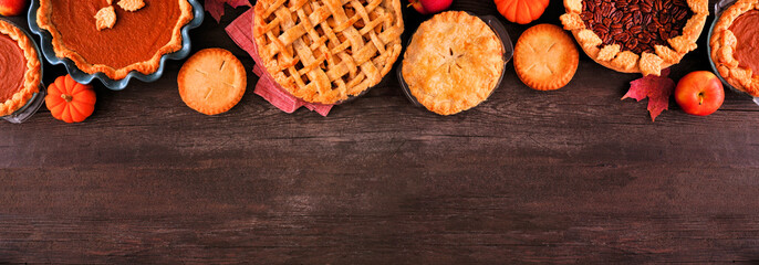 Variety of homemade fall pies. Pumpkin, apple and pecan. Overhead view top border on a dark wood background with copy space.