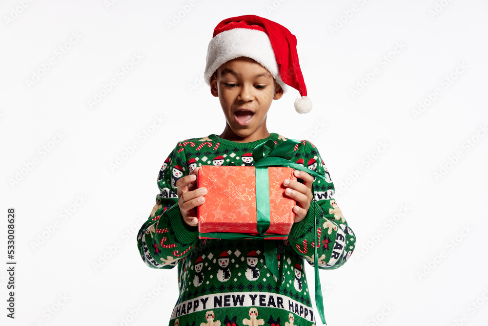 Happy smiling child in a knitted colorful sweater holds box in festive package. Boy rejoices at holiday, Christmas, New Year. Happy smiling child in a knitted colorful sweater holds box in festive package. Boy rejoices at holiday, Christmas, New Year.