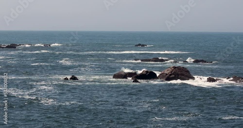 Ocean beach: camera panning from the ocean to the beach showing waves, rocks and people on the beach