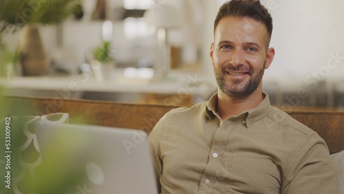 Businessman working from home on laptop computer. Happy young man sitting on couch in home office with laptop.