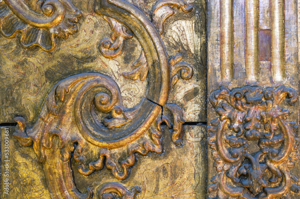 Obraz premium The background of a gilded wooden iconostasis made in the 16th century.An old carved iconostasis of the 16th century.Ancient carved patterns on the wooden surface. Religious images on a wooden surface