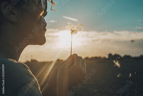 Fotografia Day dreaming leisure activity with woman blowing a dandelion outdoor in the nature park