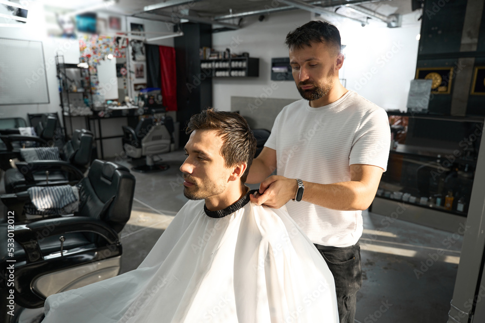 Professional barber taking care of man in haridresser chair Professional barber taking care of man in haridresser chair