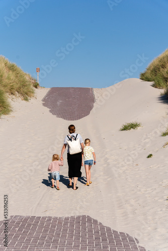 A woman walks up a dune with her two daughters on each hand on the island of Vlieland in the Netherlands.