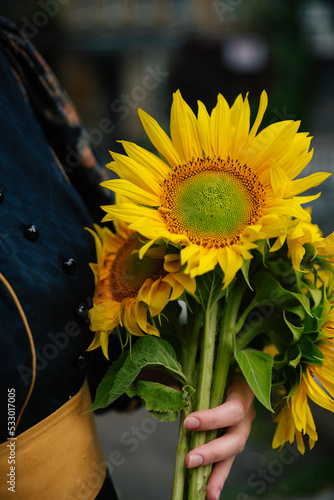 Woman in vintage retro dress holds yellow sunflowers. Flowers in hands