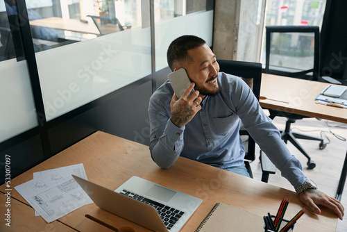 Cheerful male office worker talking on smartphone