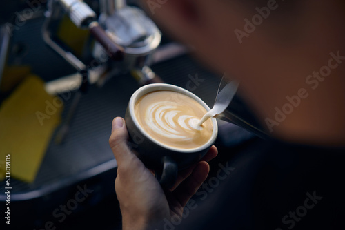 men's hands pouring milk and preparing fresh cappuccino, coffee pot and cooking concept, morning coffee