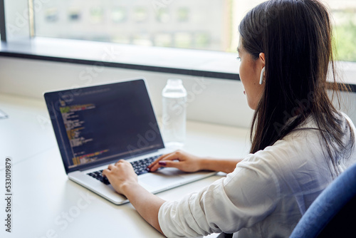 Closeup of female programmer writing code on laptop