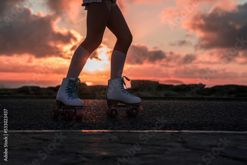 Cropped view of the active teen girl performing roller skates riding at the empty highway