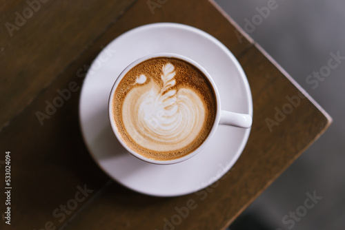 Obraz na plátně A cup of cafe latter with latte art in white cup with wooden table background