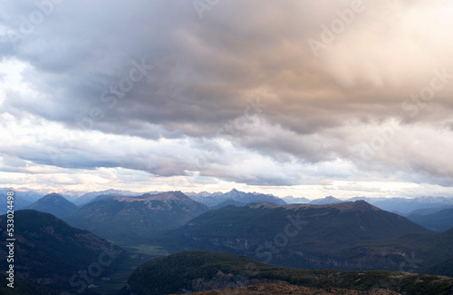 View of the mountains and forest at sunset, under a cloudy sky. 
