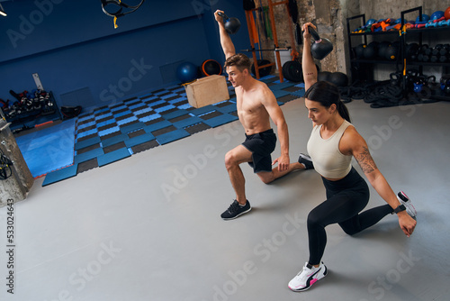 Wallpaper Mural Muscular athletic fit man and woman lifting kettlebells at gym with minimalistic interior Torontodigital.ca