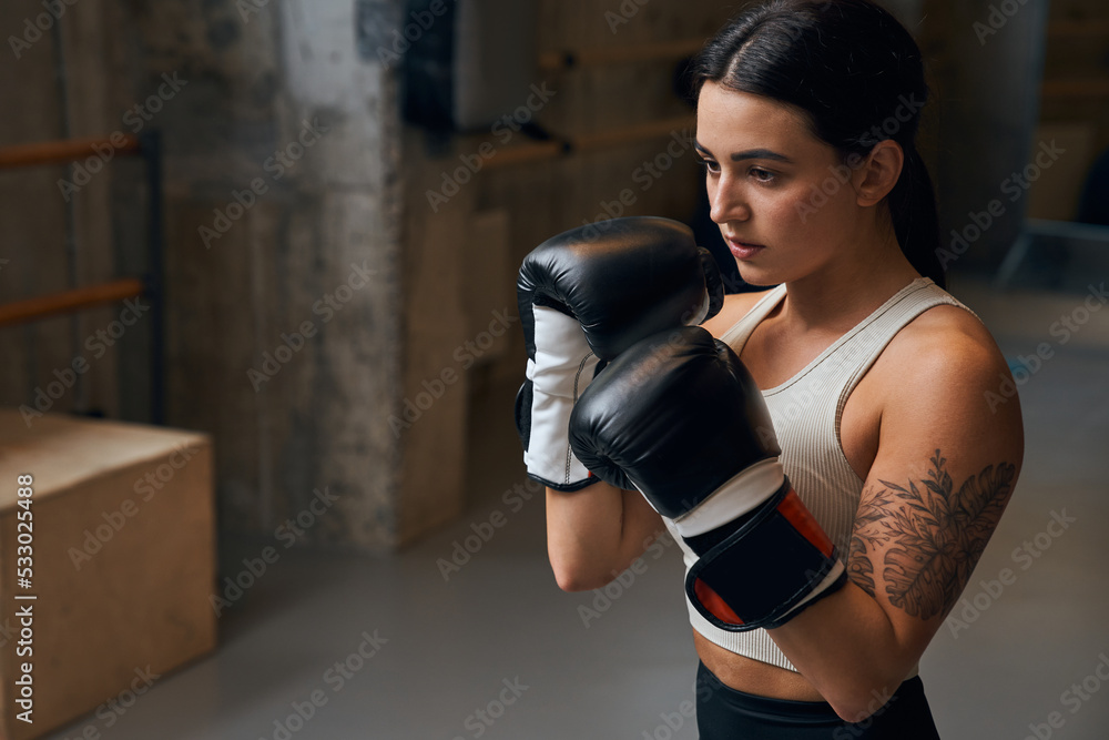 Sportswoman boxer fighting in gloves with concentrated face