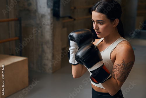 Sportswoman boxer fighting in gloves with concentrated face