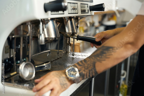 Skilled barista operating a coffee machine while making espresso