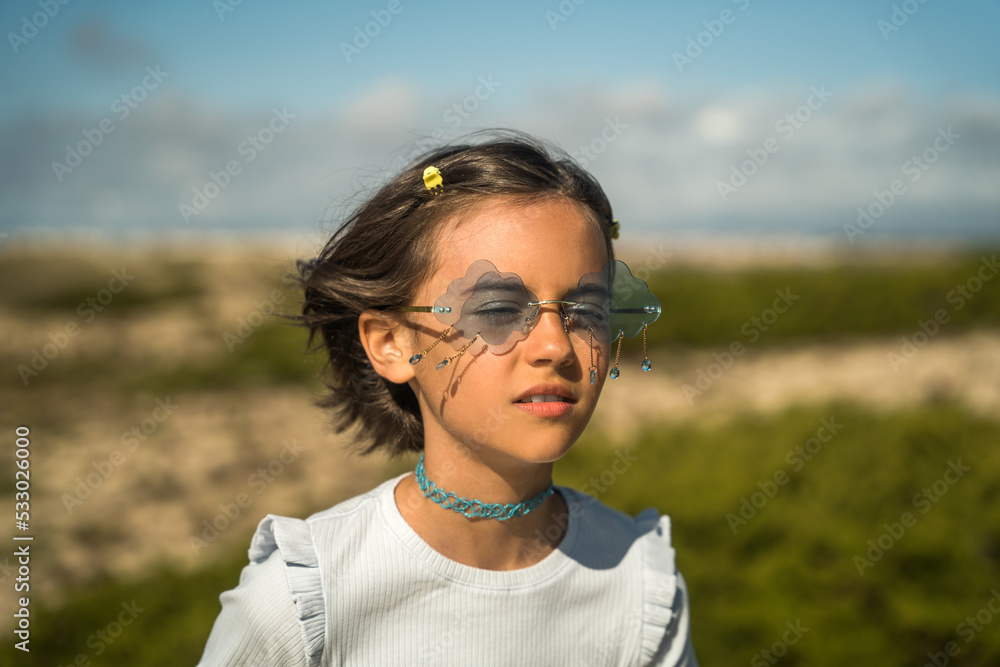 Concentrated child girl with wavy hair standing at the open air and enjoying of the fresh wind Concentrated child girl with wavy hair standing at the open air and enjoying of the fresh wind