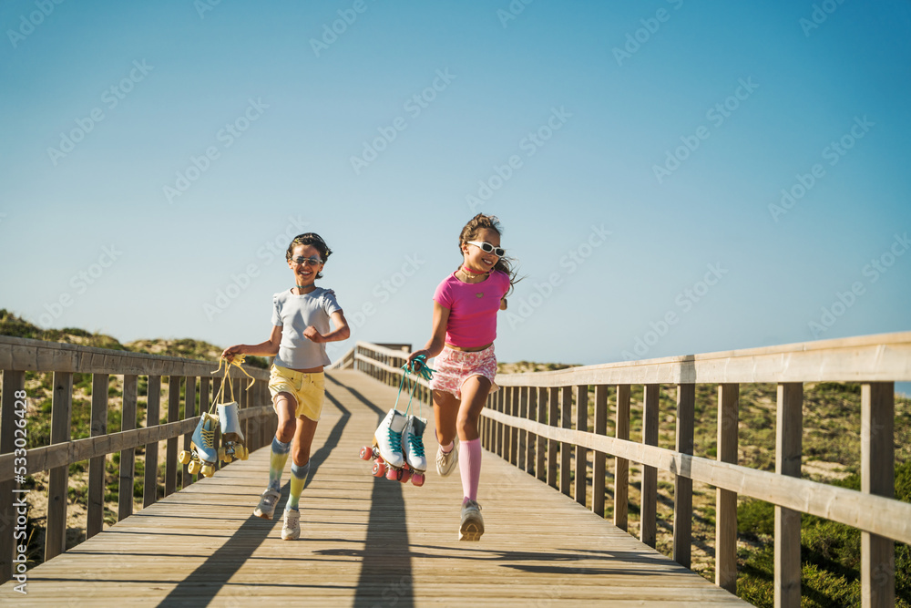 Baby girls laughing out loud and running with their roller boots at the hands