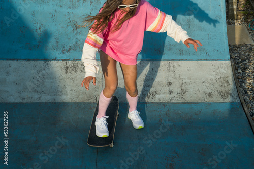 Concentrated female kid wearing sunglasses improves skateboard skills photo