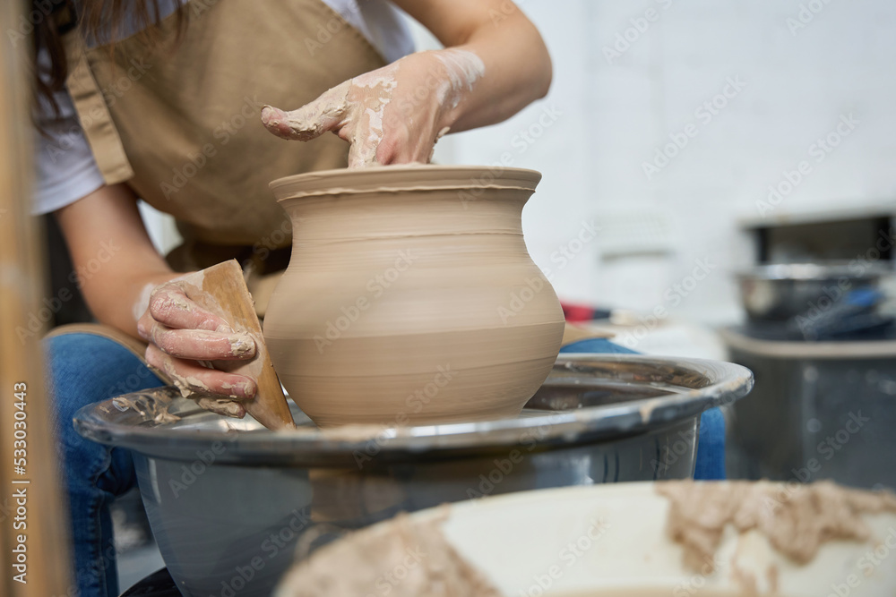 Woman potter forms earthenware on a potter wheel