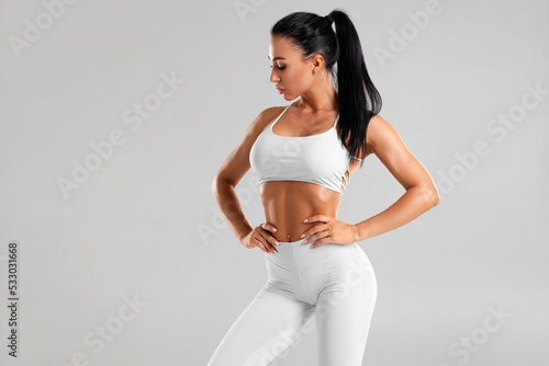 Sexy fitness woman. Beautiful athletic girl, isolated on the gray background