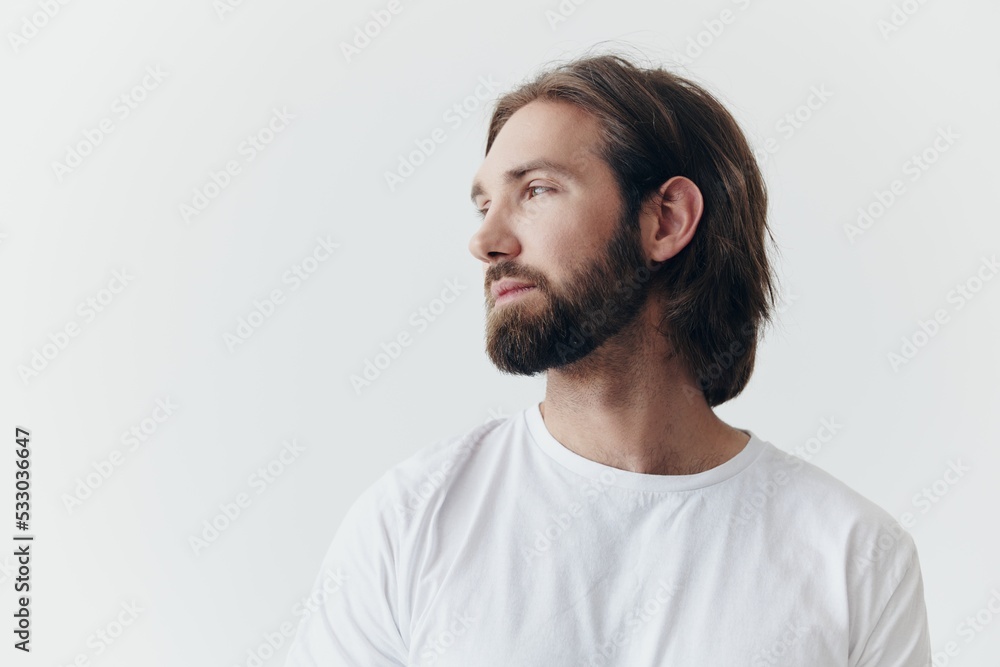 Portrait of a sad man with a black thick beard and long hair in a white t-shirt on a white isolated background Portrait of a sad man with a black thick beard and long hair in a white t-shirt on a white isolated background