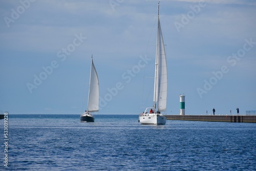 A pair of sailboats sailing down the channel 