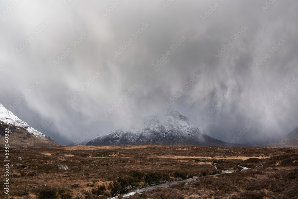Beautiful Winter landscape image of Stob Dearg Buachaille Etive Mor viewed from Rannoch Moor with snowcapped peak with heavy snow fall passing by the mountain Beautiful Winter landscape image of Stob Dearg Buachaille Etive Mor viewed from Rannoch Moor with snowcapped peak with heavy snow fall passing by the mountain