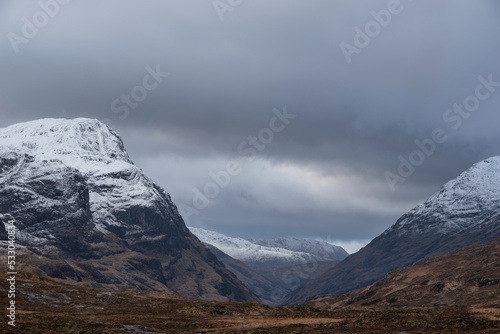 Stunning Winter landscape image of snowcapped Three Sisters mountain range in Glencoe Scottish Highands with dramatic sky photo