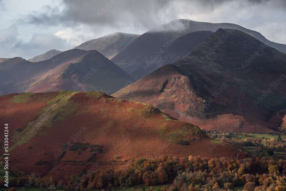 Obraz premium Beautiful landscape Autumn image of view from Walla Crag in Lake District, over Derwentwater looking towards Catbells and distant mountains with stunning Fall colors and light