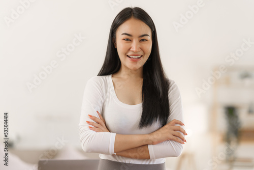 Confident smiling asian woman in creative home office looking at camera.