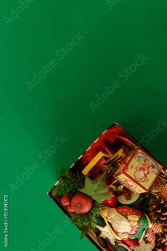 shoebox with decorations and christmas figures messed up on green background. christmas time.