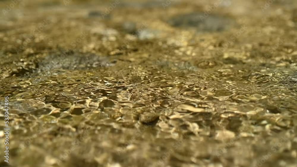 Sunlight effects on water from a mountain river in summer (slow motion, bokeh)