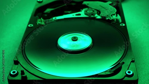 Disassembled  hard disk drive in the dark with a green light. Start and stop of hdd, how it works. HDD repair, Data Recovery, electronic technologies.