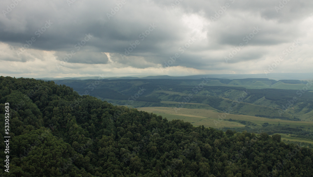 Panoramic view of a beautiful valley blurred in haze and green hills with trees against a cloudy sky in Kislovodsk russia
